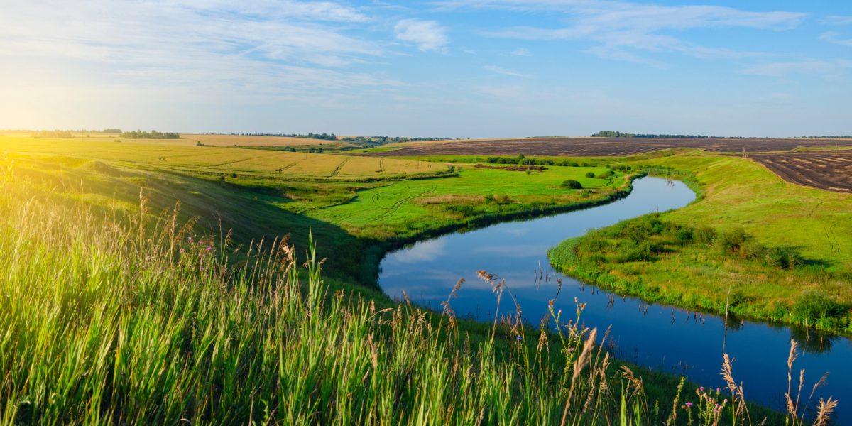 Beautiful view of river curve,green and yellow fields illuminated by the warm light of rising sun.